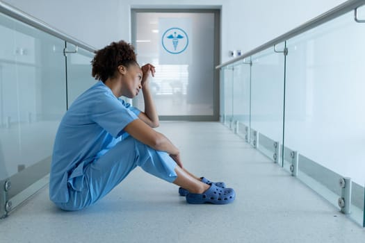 African american female doctor sitting in hospital corridor taking rest. medicine, health and healthcare services.
