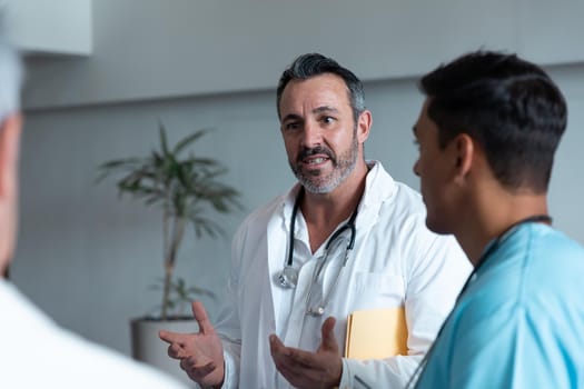 Diverse male doctors standing in hospital corridor and having discussion. medicine, health and healthcare services.