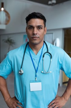 Portrait of mixed race male doctor with stethoscope wearing scrubs in hospital. medicine, health and healthcare services during covid 19 coronavirus pandemic.