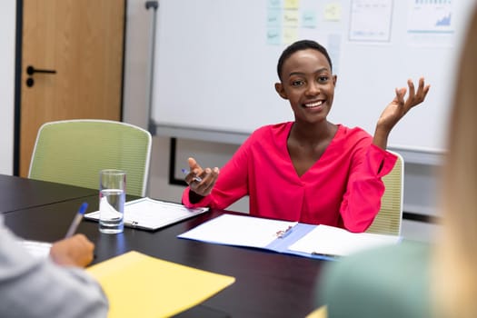 African american businesswoman in discussion at work smiling to business colleagues. working person in a modern office