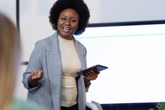 African american businesswoman holding digital tablet and giving presentation to business colleagues. business in a modern office.