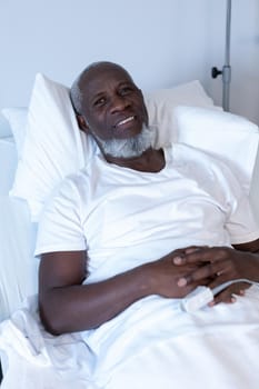 Portrait of african american male patient lying on hospital bed smiling to camera. medicine, health and healthcare services.