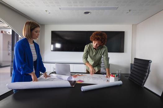 Diverse male and female colleagues in office discussing over blueprint document. independent creative design business.