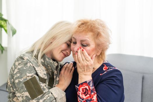 Soldier woman returning home to her family, embracing his mother, close up.
