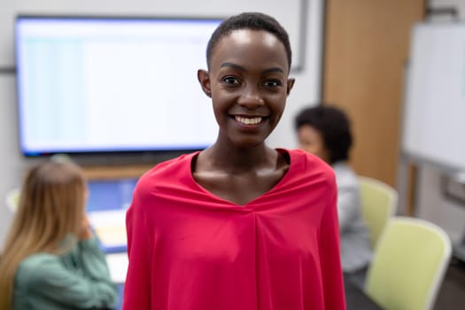 Portrait of african american businesswoman in meeting room looking to camera and smiling. business person at work in modern office.