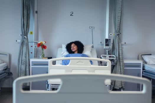 Thoughtful african american female patient lying in hospital bed looking to side. medicine, health and healthcare services.