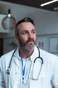 Portrait of caucasian male doctor with stethoscope wearing lab coat in hospital. medicine, health and healthcare services during covid 19 coronavirus pandemic.