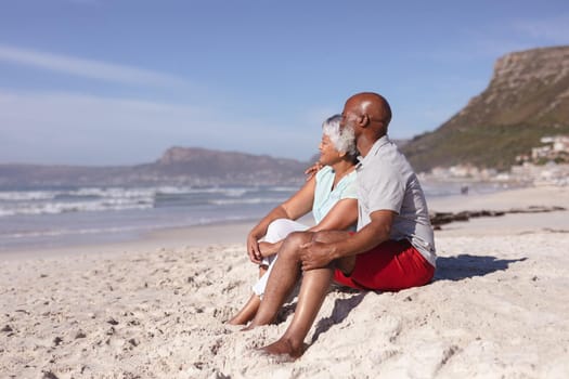 Happy senior african american couple sitting together on the beach. travel vacation retirement lifestyle concept