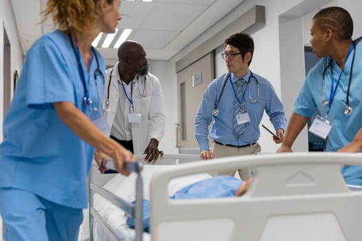 Diverse group of male and female doctors transporting patient on hospital bed. medicine, health and healthcare services.