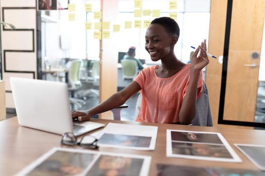 Happy african american businesswoman sitting at desk having video call conversation using laptop. independent creative business