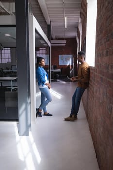 Diverse male and female colleagues at work standing discussing in corridor. independent creative design business.