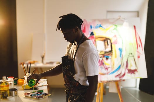 African american male painter at work holding paint in art studio. creation and inspiration at an artists painting studio.