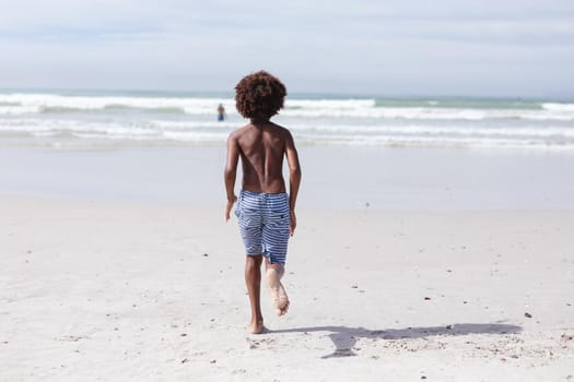 Rear view of african american boy running on the beach. travel vacation summer beach concept