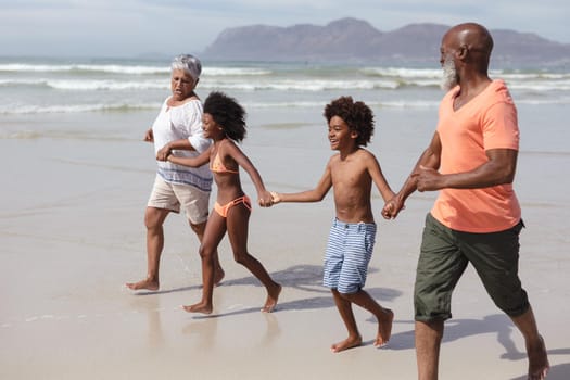 African american grandparents and grandchildren holding hands walking on the beach. travel vacation summer beach concept