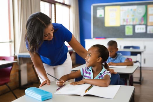 African american female teacher teaching african american girl in the class at elementary school. school and education concept