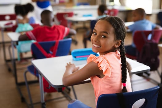 Portrait of african american girl smiling while sitting in the class at elementary school. school and education concept