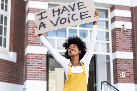 Portrait of mixed race woman holding placard. equal rights and justice protestors on demonstration march.