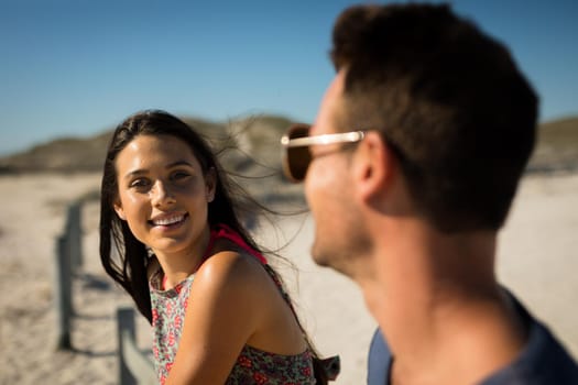 Happy caucasian couple sitting on beach by the sea woman looking to camera. healthy outdoor leisure time by the sea.