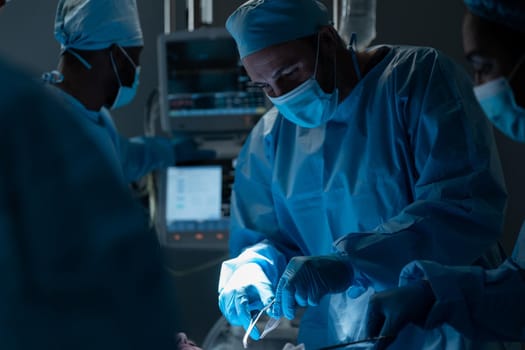 Caucasian male surgeon wearing face mask and protective clothing during operation in hospital. operating theatre. medicine, health and healthcare services during covid 19 coronavirus pandemic.