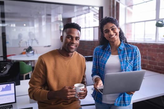 Happy diverse male and female colleagues at work standing discussing in front of laptop. independent creative design business.