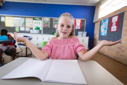 Portrait of caucasian girl sitting on her desk in the class at elementary school. school and education concept