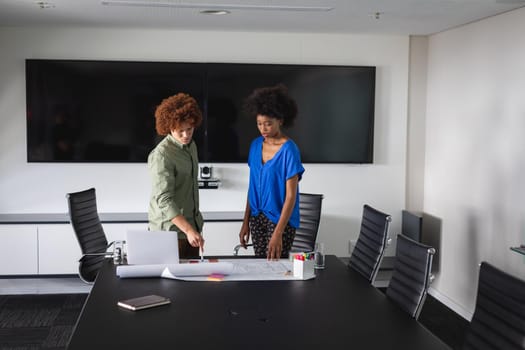 Diverse male and female colleagues in office discussing over blueprint document. independent creative design business.