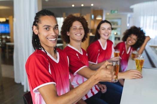 Diverse group of male and female sports fans having beer watching game at bar. sports fan friends socialising and drinking at bar.