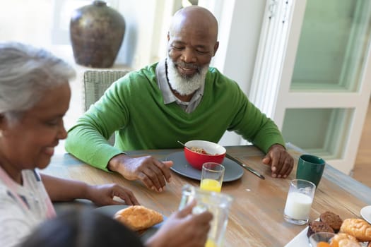Happy african american family sitting at table smiling during breakfast and smiling. family enjoying quality free time together.