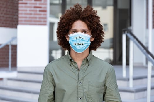 Portrait of mixed race man wearing a face mask with writing. equal rights and justice protestors on demonstration march during coronavirus covid 19 pandemic.