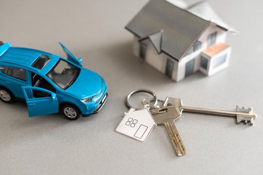 flat lay toy car, toy house, keys and money on the table.