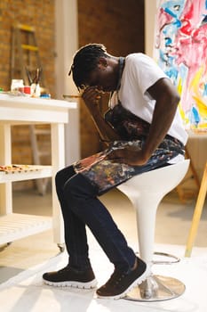 Tired african american male painter at work in art studio. creation and inspiration at an artists painting studio.