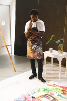 African american male painter at work looking at artwork in art studio. creation and inspiration at an artists painting studio.