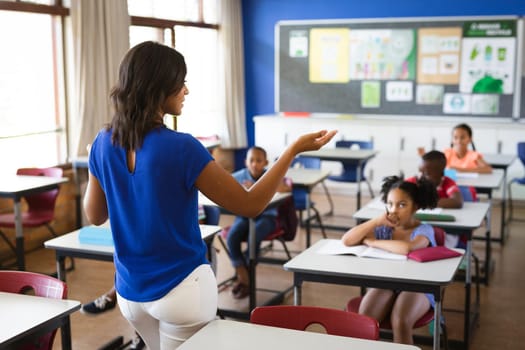 Rear view of african american female teacher teaching students in the class at elementary school. school and education concept