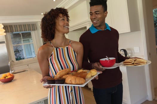 Happy african american couple preparing food for breakfast for family and smiling. family enjoying quality free time together.