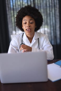 African american female doctor sitting making video call consultation. telemedicine online with doctor during quarantine lockdown.