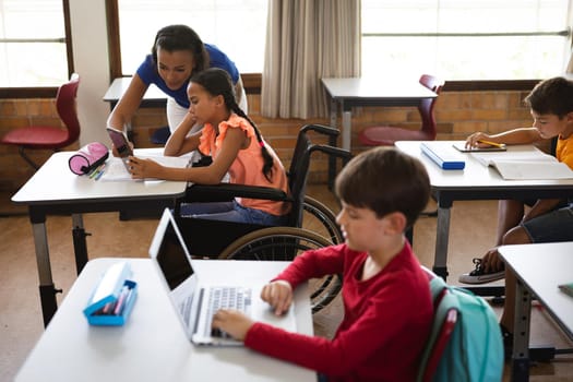 African american female teacher teaching disabled girl to use digital tablet at elementary school. school and education concept