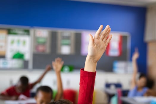 Raised hand of caucasian boy for participation in the class at elementary school. school and education concept