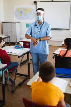 Female health worker showing students to use hands sanitizer in class at elementary school. education back to school health safety during covid19 coronavirus pandemic.