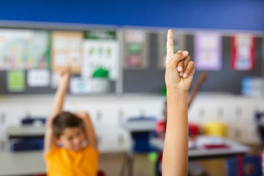 Boy raising his hand for participation in the class at elementary school. school and education concept