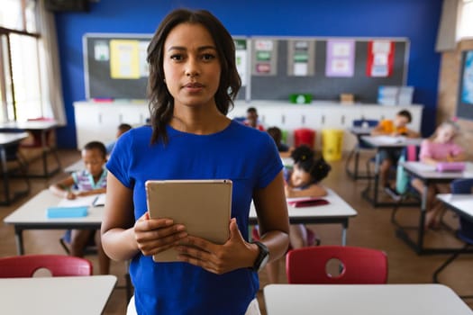 Portrait of african american female teacher holding digital tablet in the class at school. school and education concept