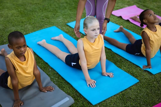 Mid section of female teacher correcting the form of caucasian girl in the garden at school. school and education concept