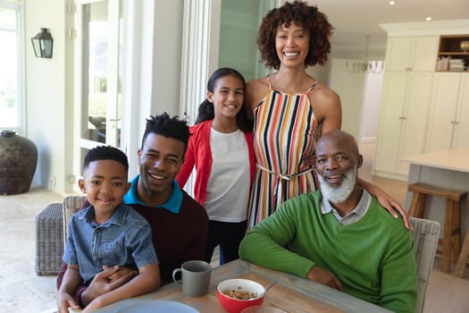 Portrait of smiling african american multi generation family sitting at table during breakfast. family enjoying quality free time together.