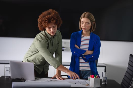 Diverse male and female colleagues in office discussing over blueprint document. independent creative design business.