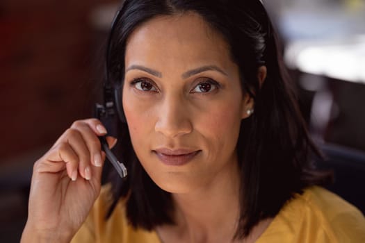 Portrait of happy caucasian businesswoman wearing phone headset sitting at desk smiling to camera. working in business at a modern office.