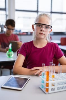 Portrait of caucasian girl wearing protective glasses in science class at laboratory. school and education concept