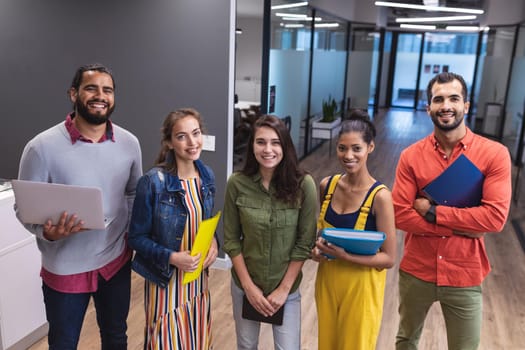 Portrait of diverse group of creative colleagues looking at camera and smiling. modern office of a creative design business.