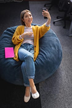 Mixed race businesswoman chilling in office relaxing space lying in beanbag. independent creative design business.