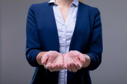 Midsection of caucasian businesswoman showing her hands, isolated on grey background. business technology, communication and growth concept.