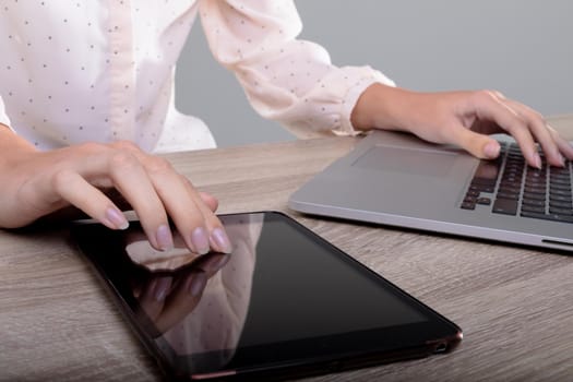 Midsection of caucasian businesswoman using laptop and tablet, isolated on grey background. business, technology, communication and growth concept.