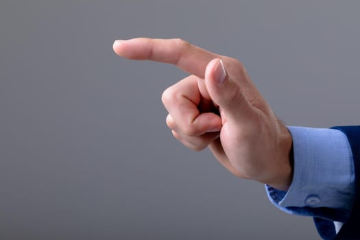 Midsection of caucasian businessman pointing with his finger, isolated on grey background. business technology, communication and growth concept.